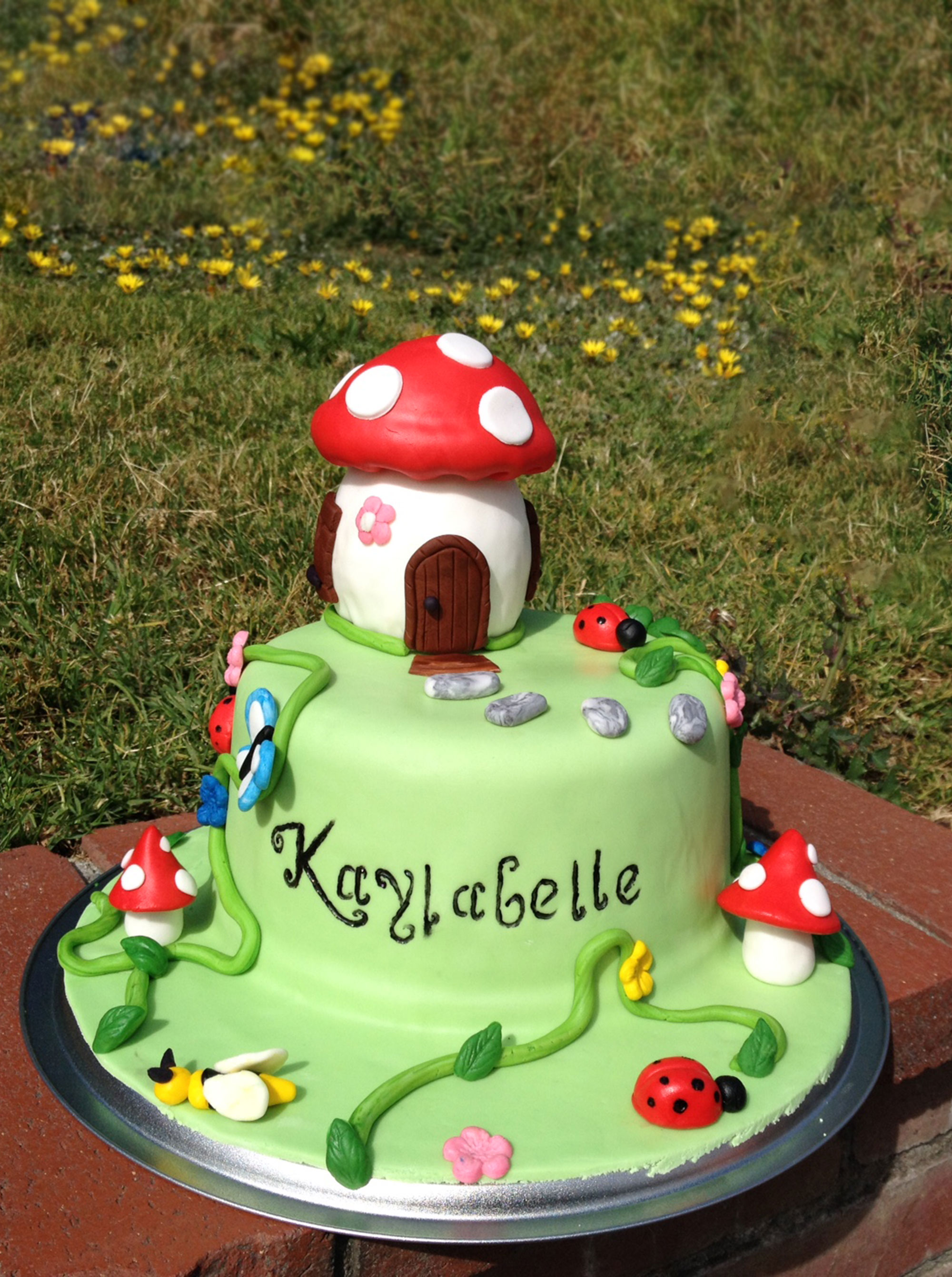 birthday cake in the shape of a green hill with a mashroom house